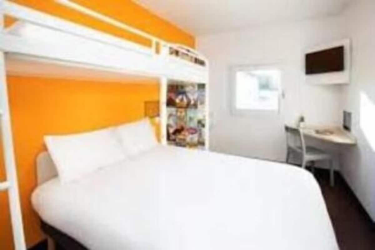 Una habitación de hotel con literas, un escritorio y un televisor.