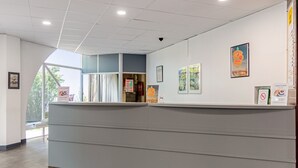 A reception area with a counter, framed pictures on the wall, and a view of the outdoors.