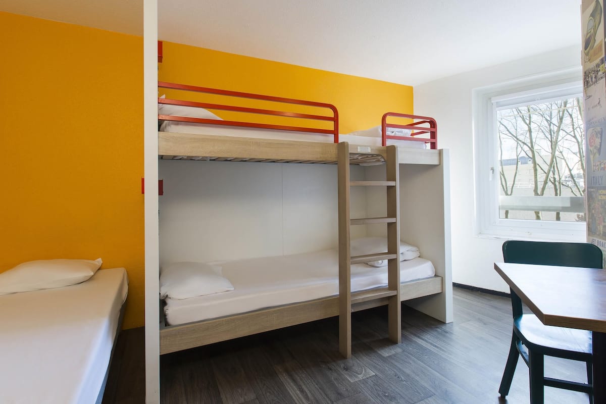 Habitación con literas, un escritorio y una silla, además de una ventana.