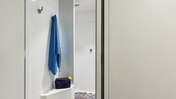 A bathroom with a shower, a towel rack, and a shelf with a bag.