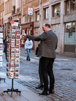 Un uomo in piedi accanto a un carretto con cartoline.