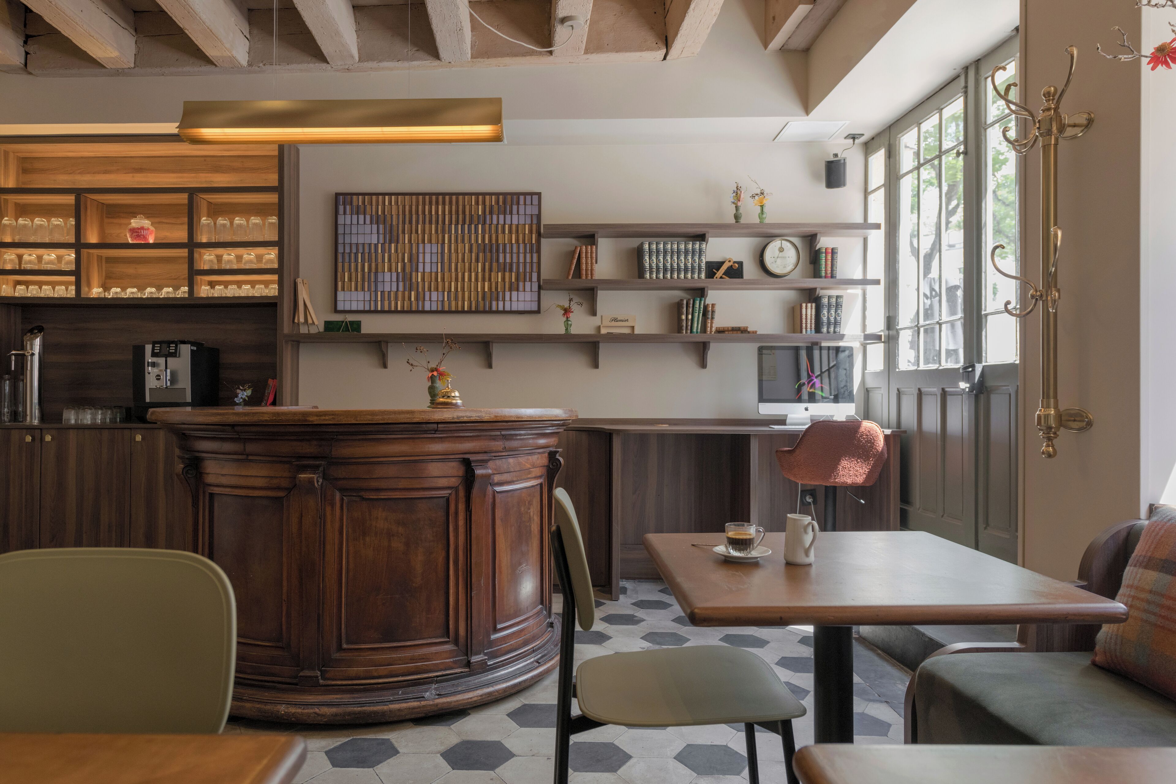 Un café acogedor con muebles de madera, una zona de bar y estantes con libros y objetos decorativos.