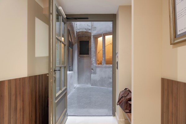 A narrow hallway with a wooden floor, a door leading to a room, and a framed certificate on the wall. - Académie Hôtel Lyon (Lyon)