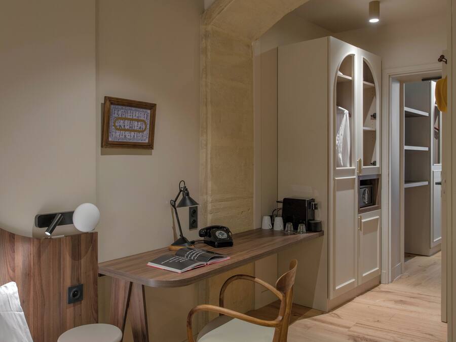 A cozy room with a wooden desk, a chair, a bed, and a wardrobe.