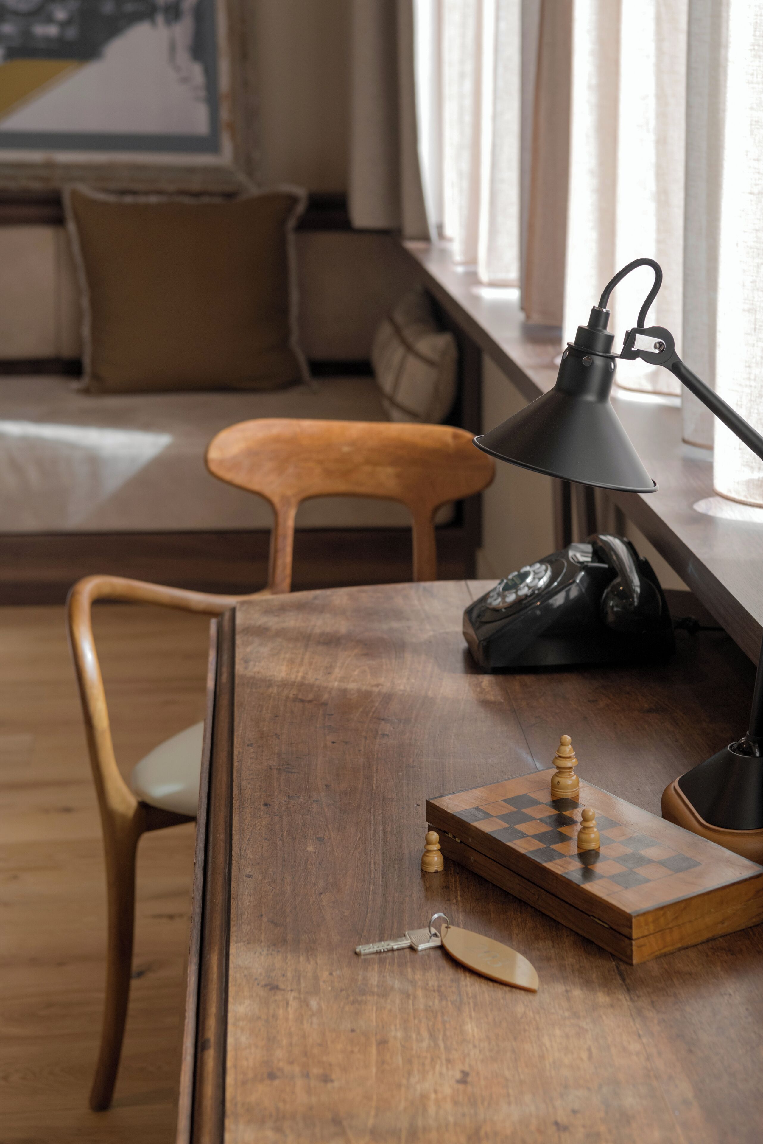 Un bureau en bois avec un jeu d’échecs, une lampe et un téléphone.