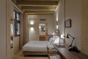 Una camera da letto con un letto, un comodino, una lampada e una scrivania con una sedia.