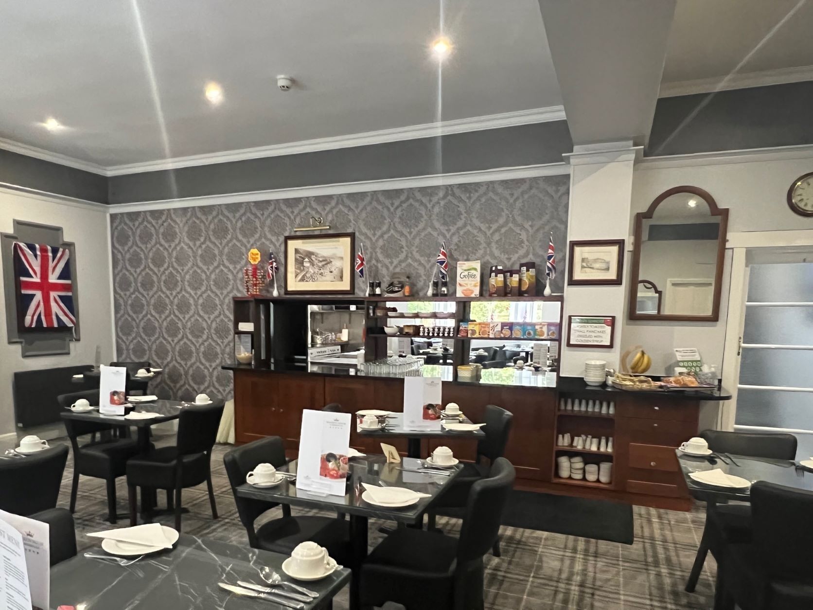 A restaurant with tables set for dining, a bar area with various items, and a wall with framed pictures and flags.