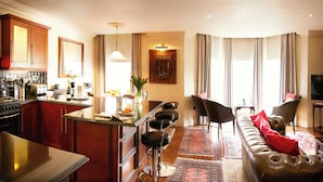 Un salon moderne avec un canapé, des fauteuils, une table basse et un téléviseur.