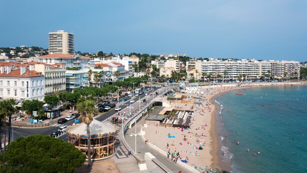 Un paysage urbain côtier avec une plage, des bâtiments et un ciel dégagé.