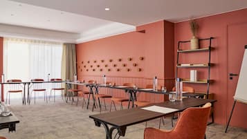 Una sala de conferencias con una mesa larga, varias sillas, una pizarra y una estantería con objetos decorativos.