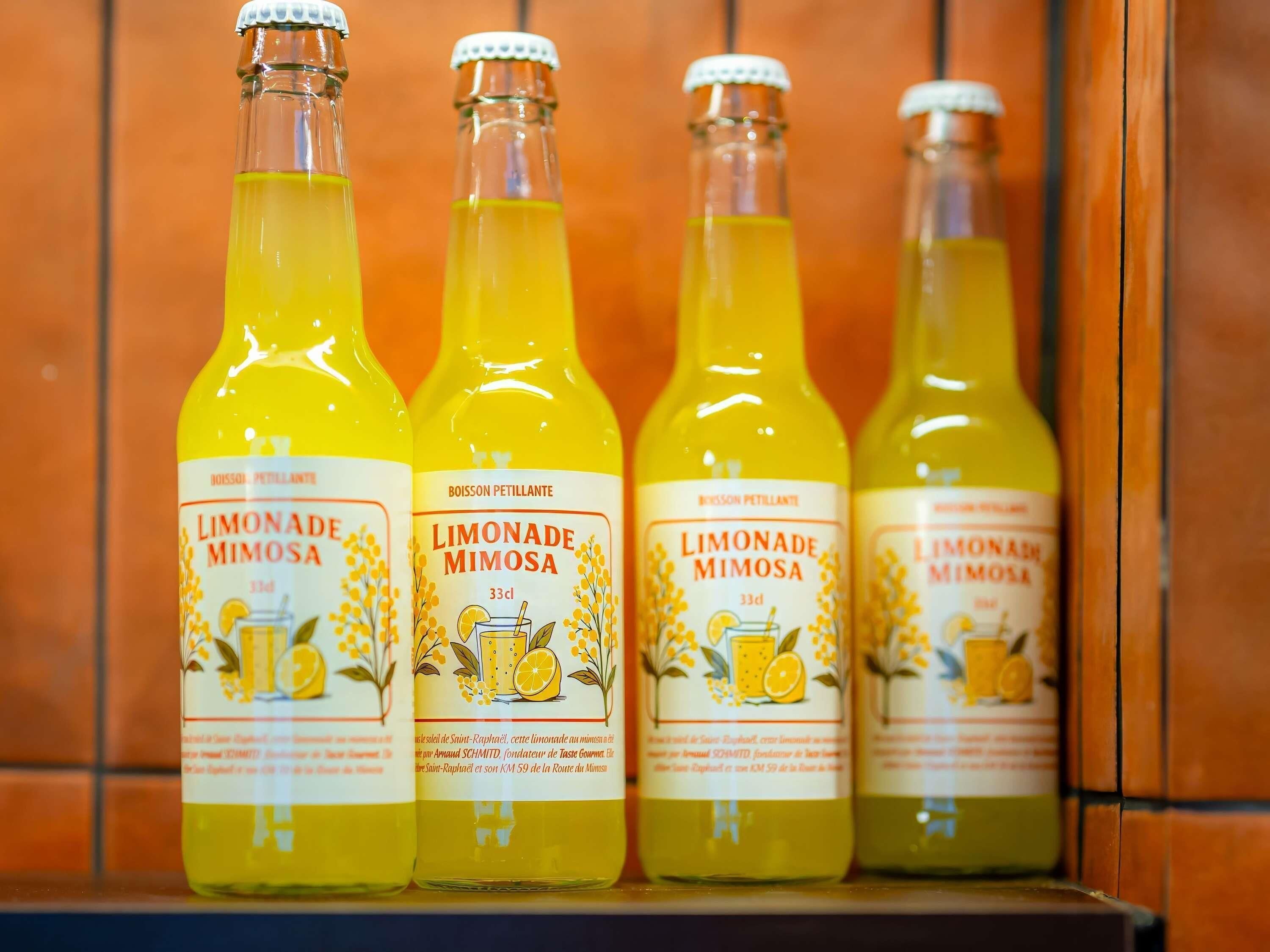 Four bottles of Limonade Mimosa on a shelf.
