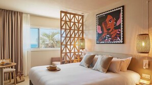 Une chambre d’hôtel avec un grand lit, un bureau, une chaise et une vue sur les palmiers.