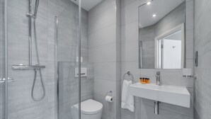 A modern bathroom with a glass-enclosed shower, a toilet, and a sink with a mirror above it. - Mornington Victor Hotel London Belgravia (London)