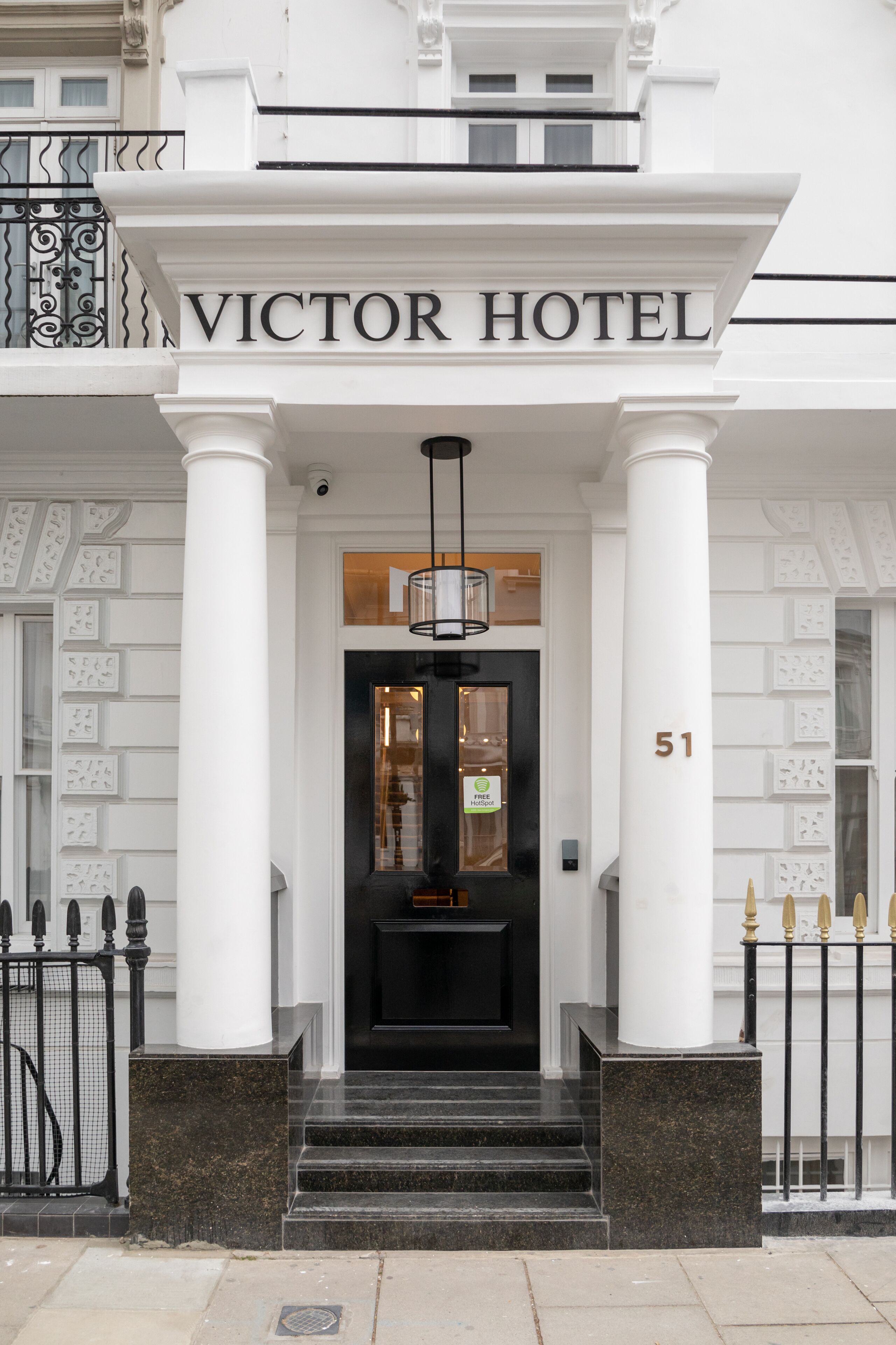 The entrance to the Victor Hotel, featuring a grand facade with large columns, a black door, and a number '51' on the right.