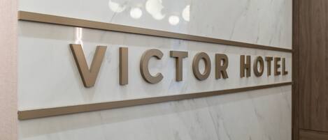 A marble wall with the text "VICTOR HOTEL" in gold letters.