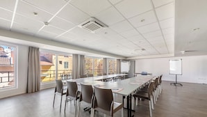 A conference room with a long table, chairs, a whiteboard, and a projector.
