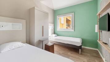 Habitación de hotel con dos camas, un escritorio, un televisor y una ventana con vistas al exterior.
