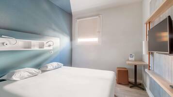 Een moderne hotelkamer met een bed, een televisie, een bureau en een raam.