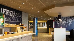 A modern cafe interior with a counter, seating area, and decorative wall art.
