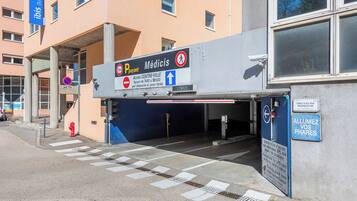A building entrance with a sign for 'Médicis' and a parking area.