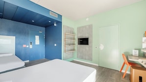 Una habitación de hotel moderna con una cama grande, un escritorio con una silla y un televisor montado en la pared.