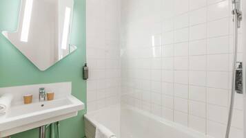 A bathroom with a sink, mirror, and shower.