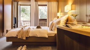 Un dormitorio con cama, mesita de noche, lámpara y vistas al exterior.