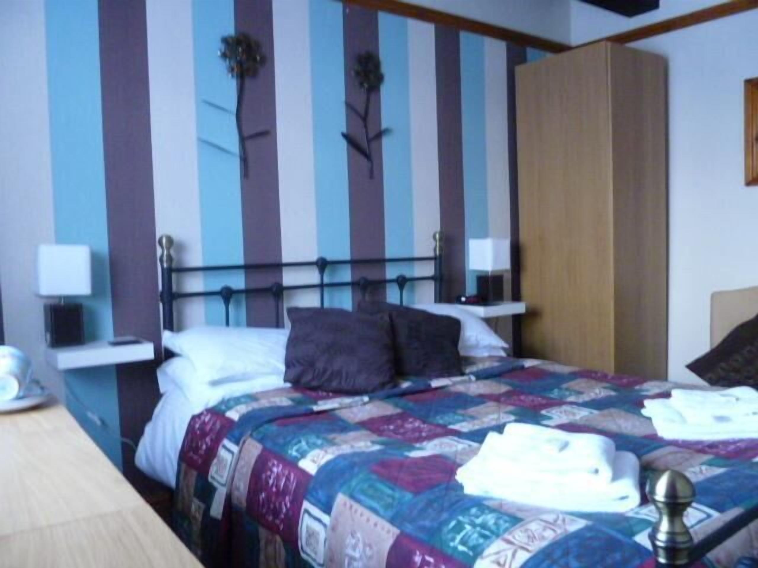 A bedroom with a bed, pillows, a nightstand, and a wardrobe.