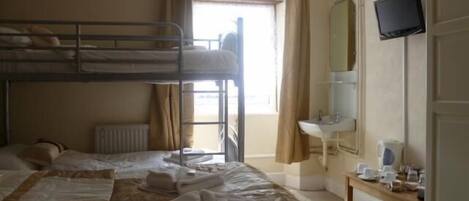 Une chambre avec un lit superposé, une fenêtre, un lavabo et un téléviseur.