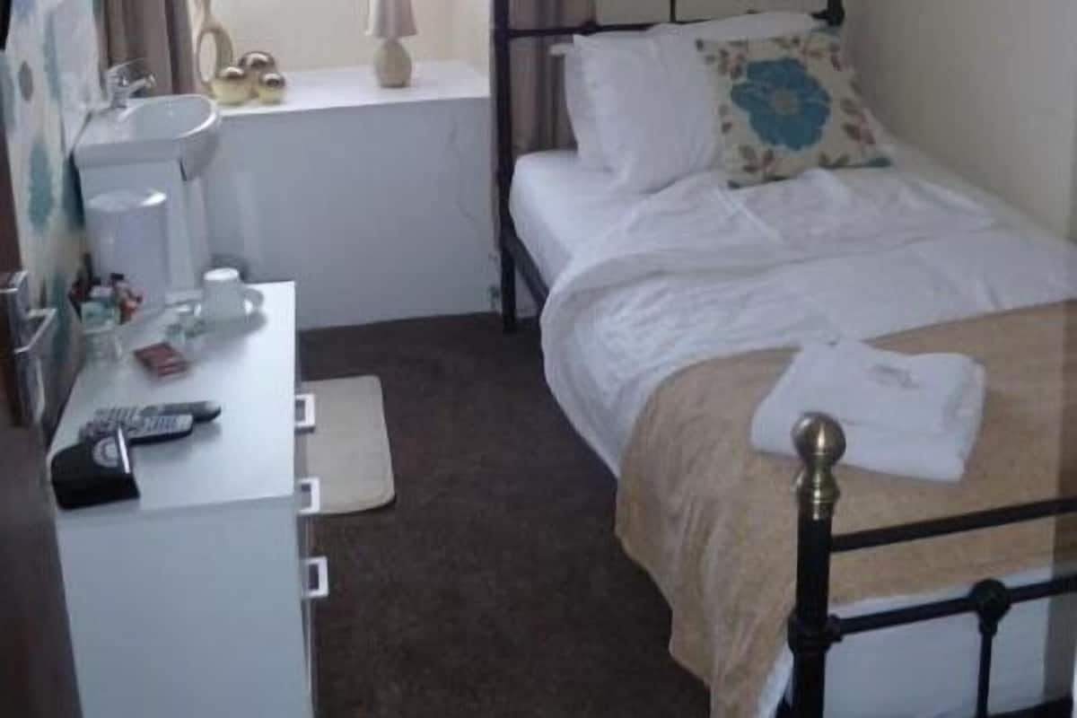 Une chambre à coucher avec un lit, une table de chevet et une fenêtre avec des rideaux.