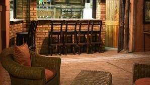 Un rincón de bar acogedor con pared de ladrillo, sillas de madera y un sofá de mimbre.