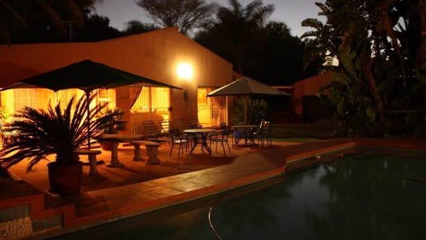 Zona de piscina con asientos exteriores y un edificio con luz cálida.