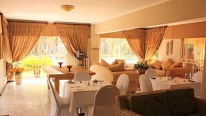 Un comedor con una mesa preparada para dos personas, un sofá y una silla de mimbre.
