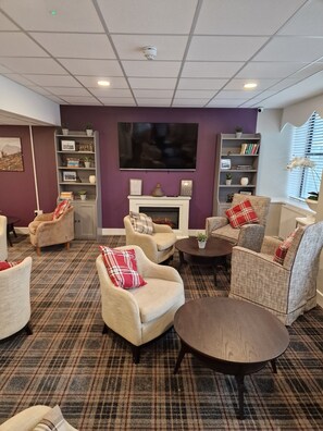 A cozy living room with a fireplace, comfortable seating, a flat-screen TV, and a bookshelf. - Britannia Inn Glasgow (Glasgow)