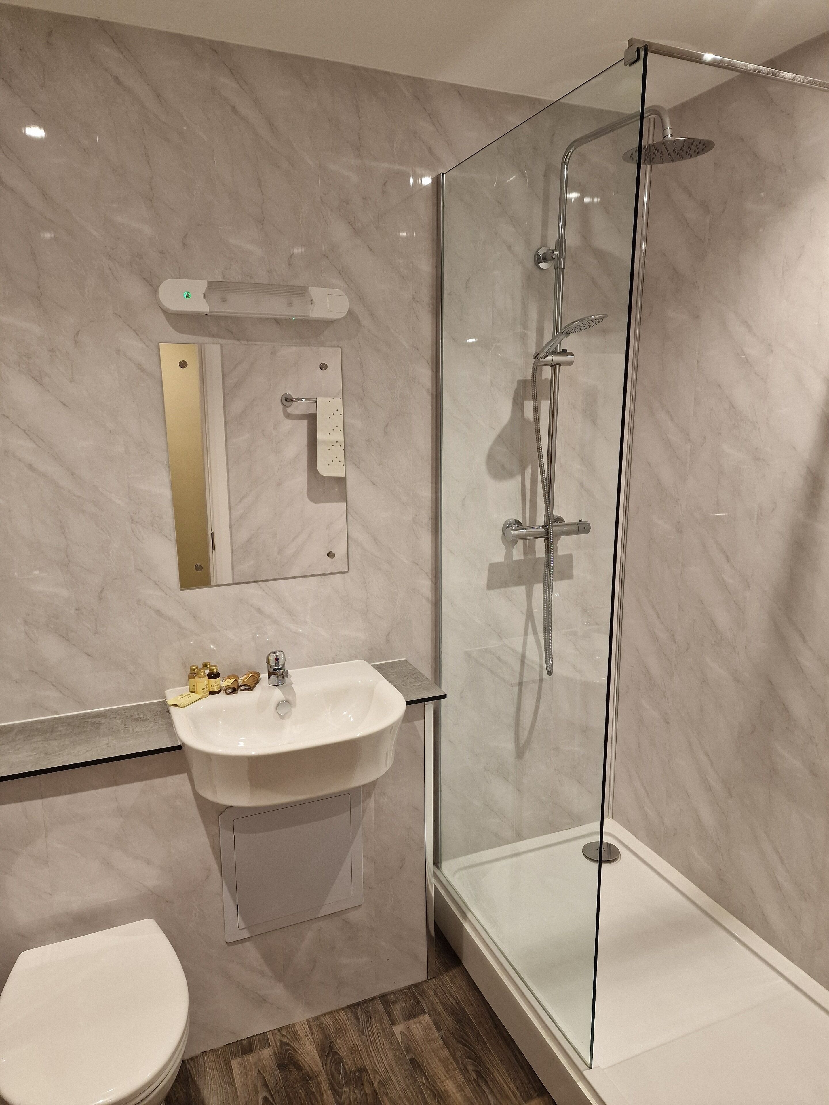 A modern bathroom with a glass-enclosed shower, a white sink, and a toilet.