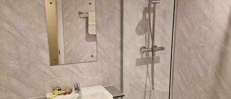 A modern bathroom with a glass-enclosed shower, a white sink, and a toilet.