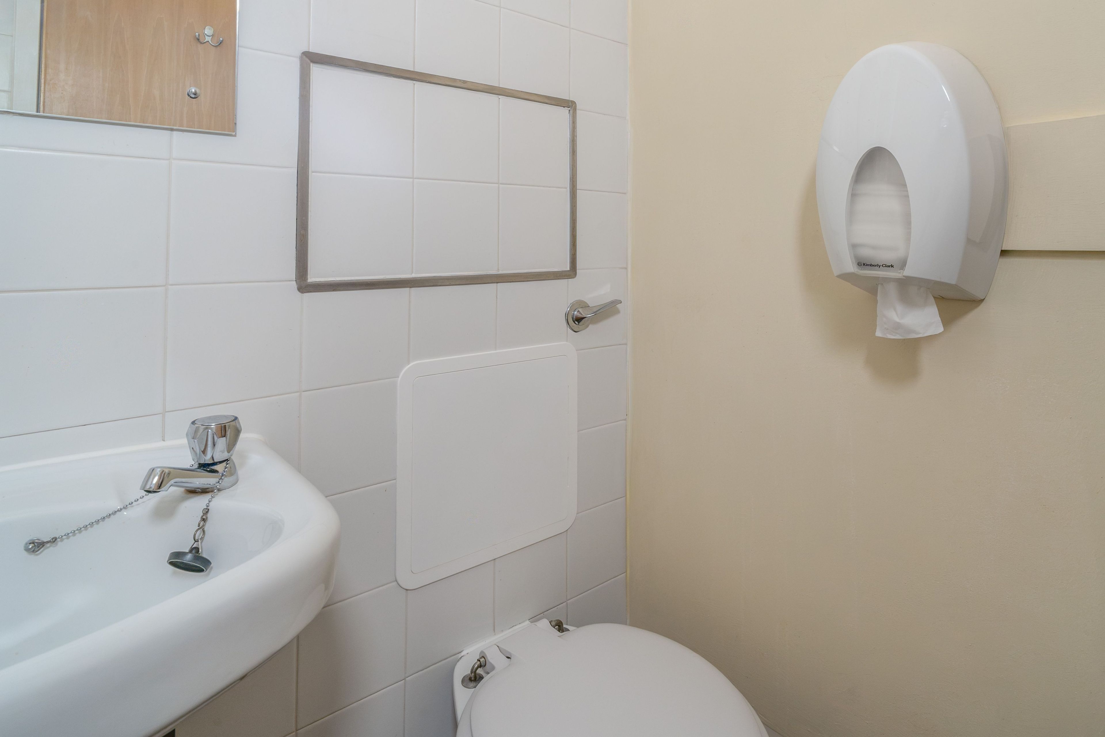 Un baño con lavamanos, inodoro y secamanos.