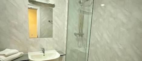 Un baño moderno con ducha de vidrio, lavamanos blanco y un inodoro.