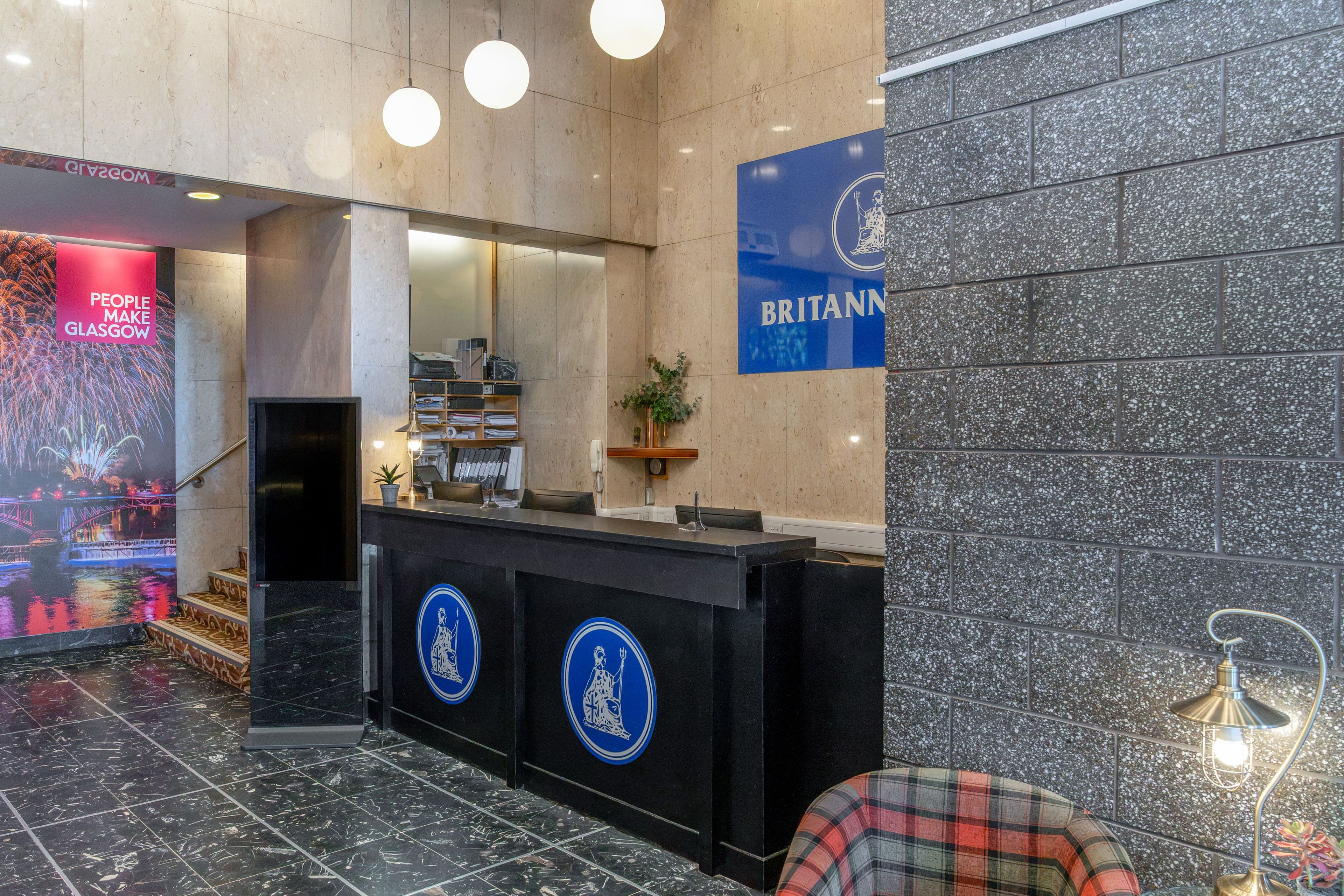 A reception area with a black counter, blue signage, and a digital screen displaying fireworks.