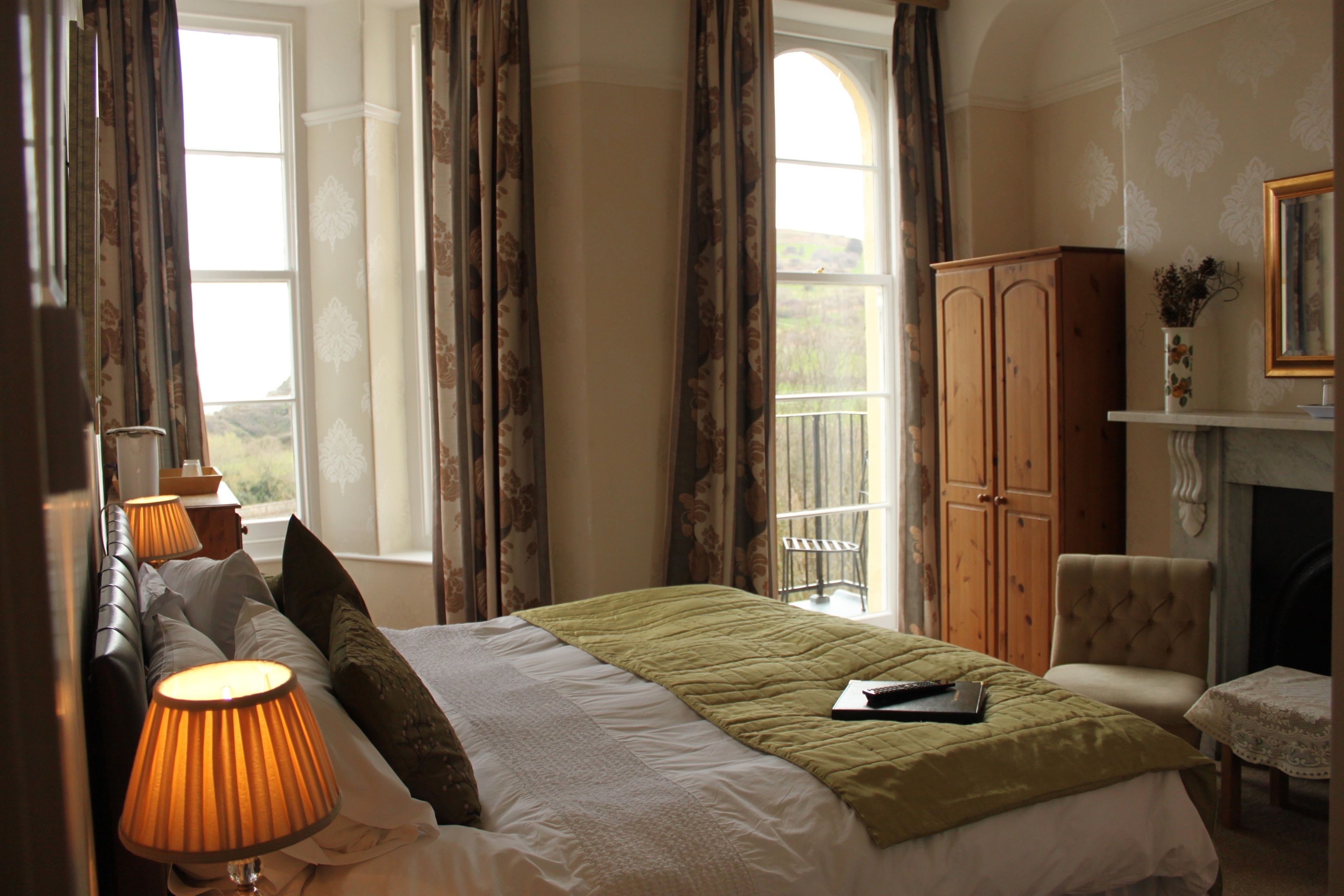 A bedroom with a bed, lamps, a chair, a cabinet, and a fireplace.
