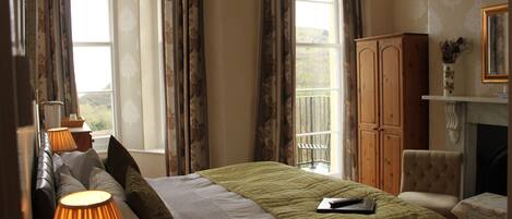 A bedroom with a bed, lamps, a chair, a cabinet, and a fireplace.