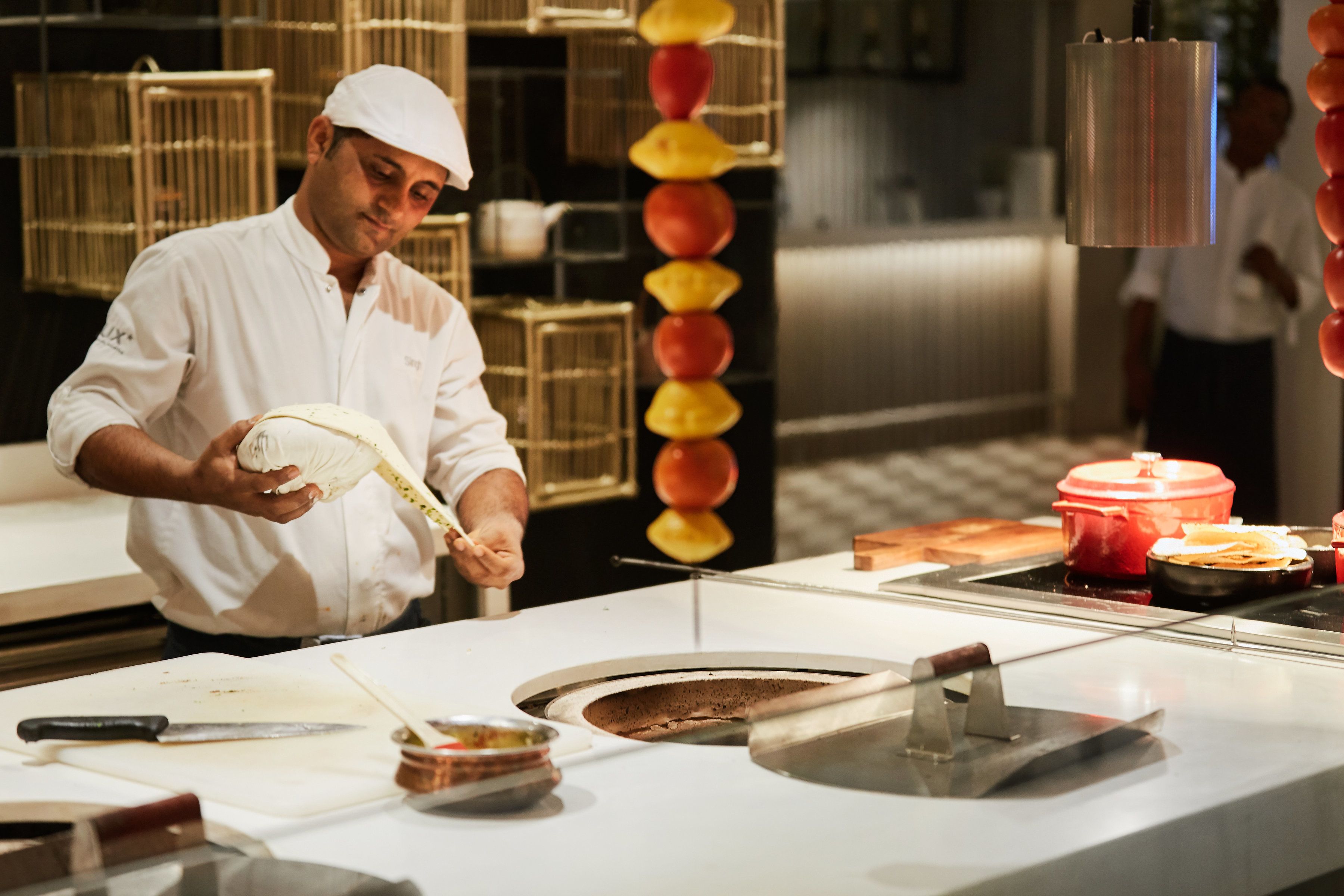 Un chef preparando comida en una cocina con una estufa grande, tabla de cortar y diversos utensilios de cocina.