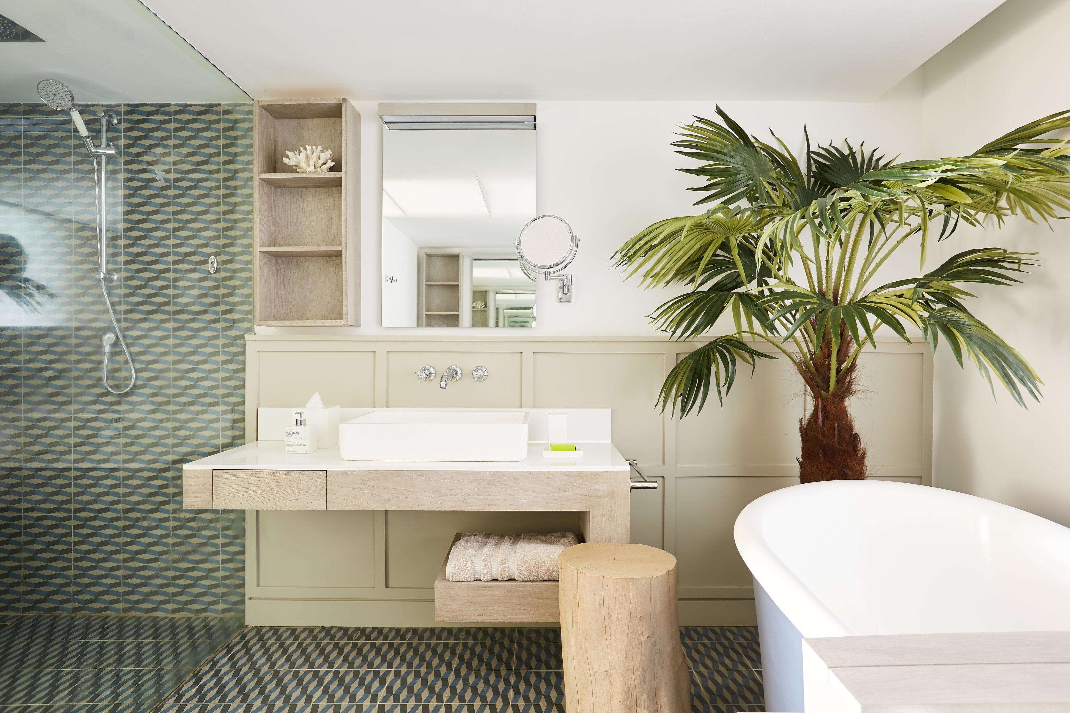 A modern bathroom with a freestanding bathtub, a large mirror, and a potted plant.