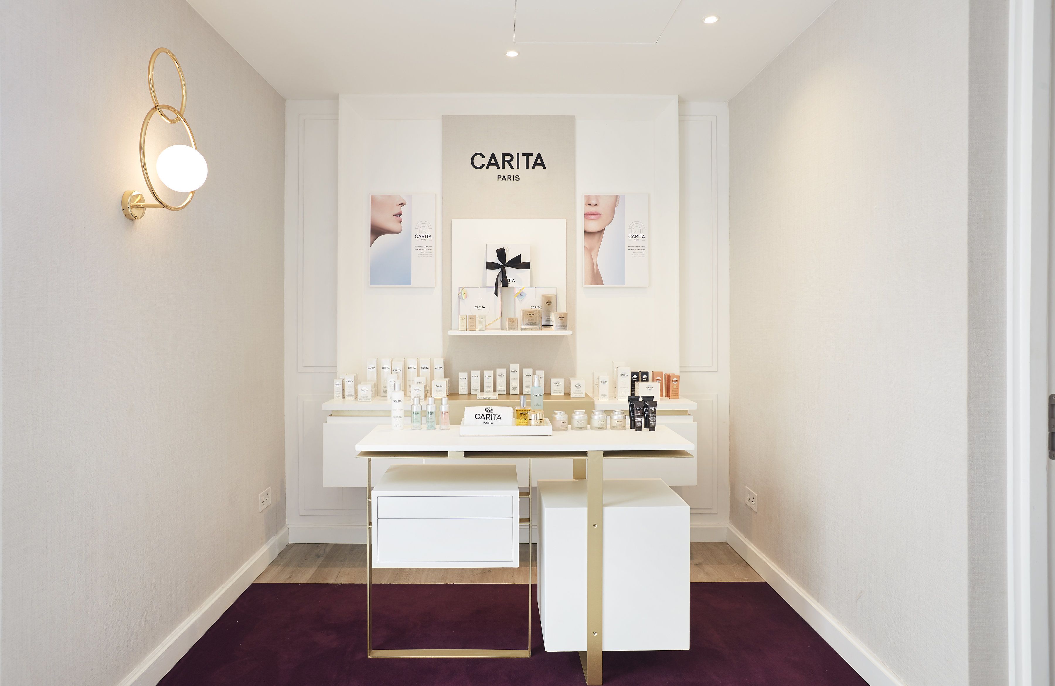 A minimalist vanity area with a white desk, a mirror, and a display of CARITA Paris skincare products.