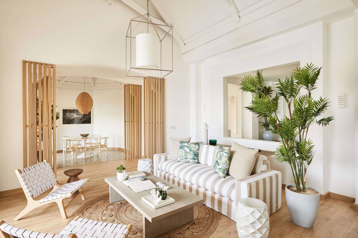 A modern living room with a striped sofa, a coffee table, and a large potted plant.