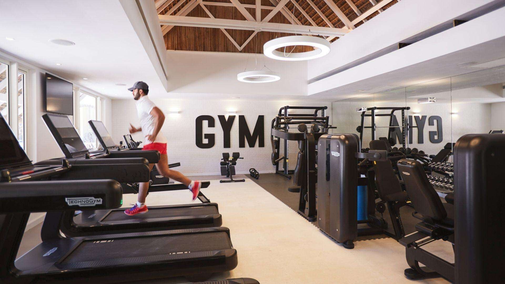 A gym with treadmills, weight machines, and a large wall with the word "GYM".