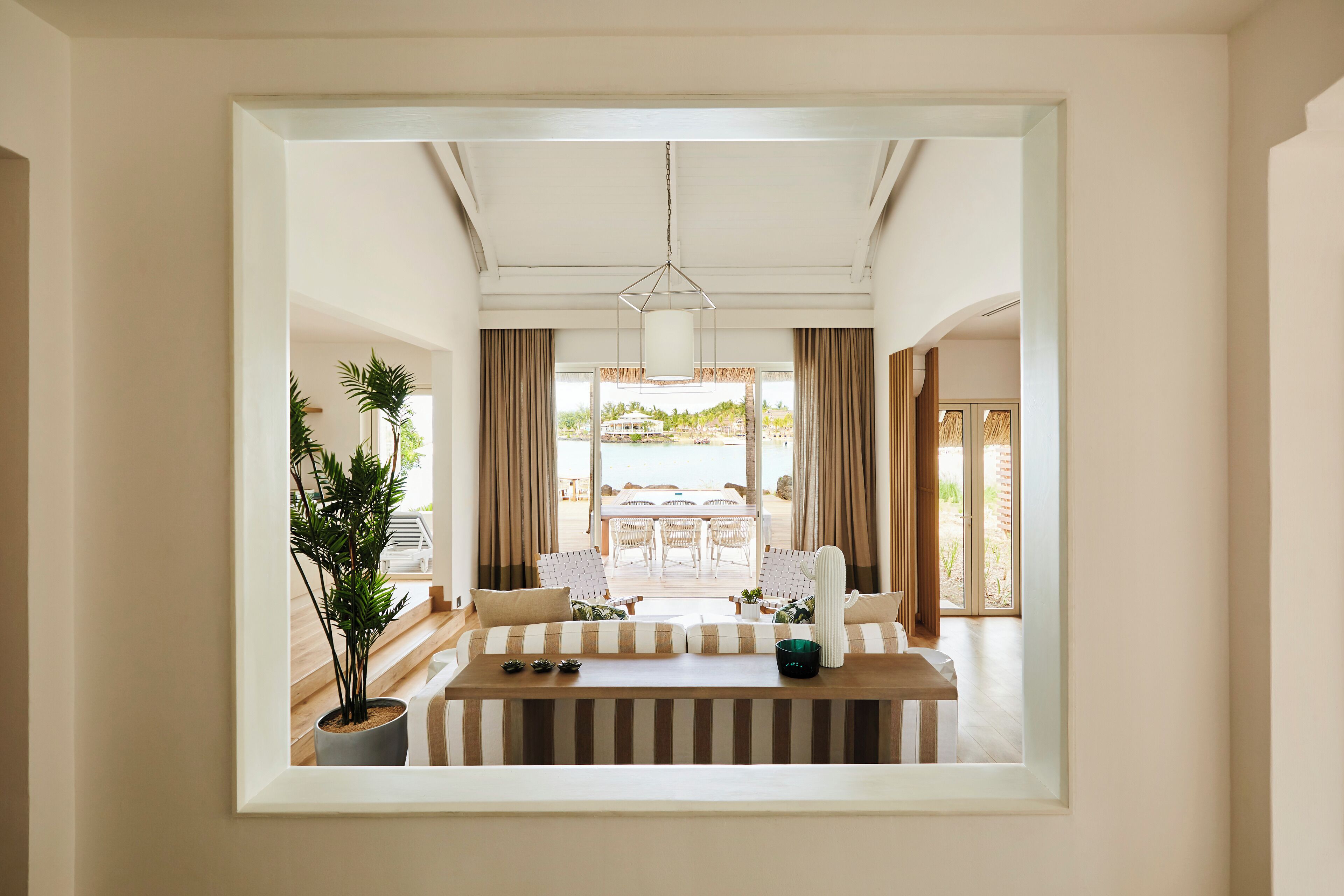 A spacious room with a wooden bench, a dining table with chairs, and a view of the outdoors.