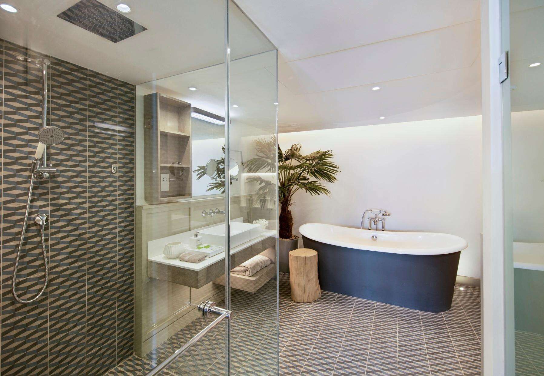 A modern bathroom with a glass-enclosed shower, a freestanding bathtub, and a vanity with a mirror.