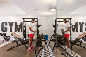 A gym with weightlifting equipment, benches, and dumbbells.