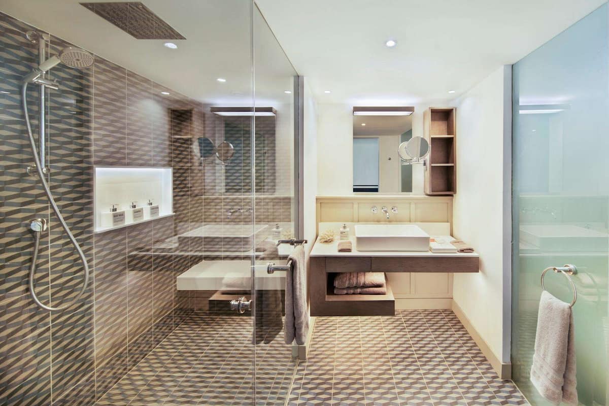 A modern bathroom with a glass-enclosed shower, a vanity with a large mirror, and a sink.